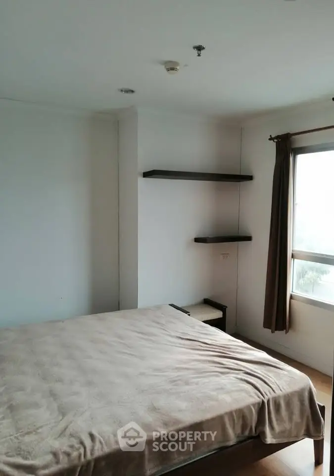 Spacious bedroom with natural light and modern shelving in a cozy apartment.