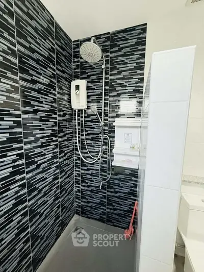 Modern bathroom with stylish black tile shower and sleek fixtures.