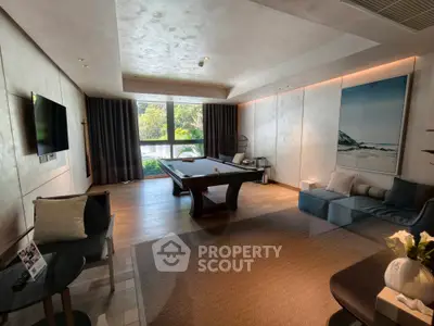 Luxurious living room with pool table and modern decor, featuring large windows and stylish furnishings.