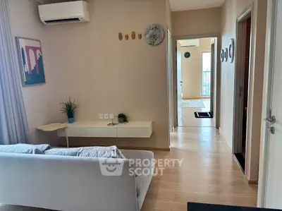 Modern living room with stylish decor and natural light, featuring a cozy sofa and wall-mounted air conditioner.