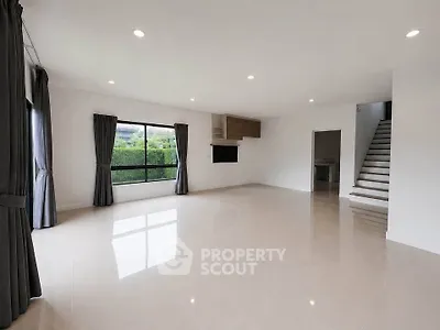Spacious modern living room with large windows and elegant staircase