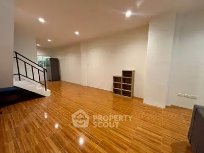 Spacious open-plan living area with wooden flooring and modern staircase, ideal for stylish urban living.