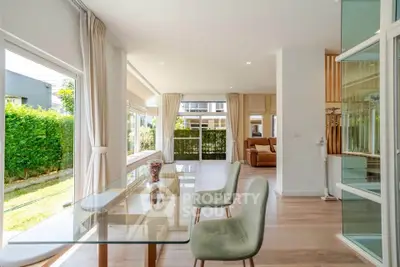 Spacious modern living room with large windows and garden view, featuring elegant dining area and stylish decor.