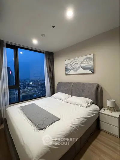 Modern bedroom with city view, featuring a cozy bed and stylish decor.