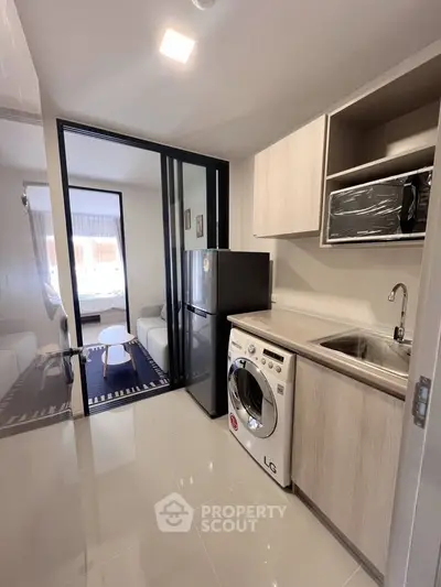 Modern kitchen with washing machine and fridge in sleek apartment