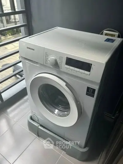 Modern Samsung washing machine in sleek laundry area with tiled flooring.