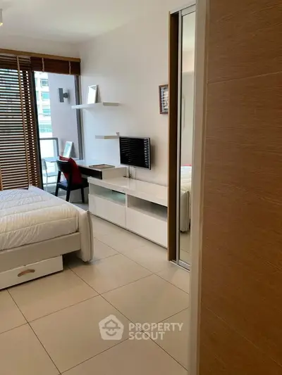Modern bedroom with sleek design, featuring a cozy bed, wall-mounted TV, and a stylish workspace near a large window.