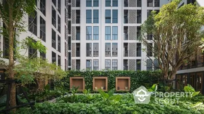 Modern apartment building with lush green courtyard and contemporary design.