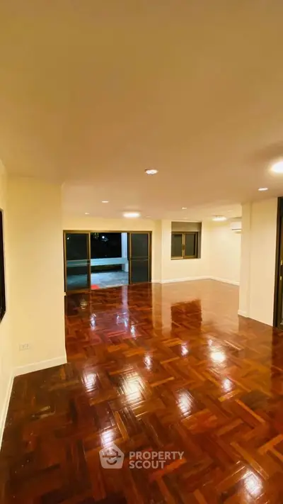 Spacious living room with polished wooden floors and large windows