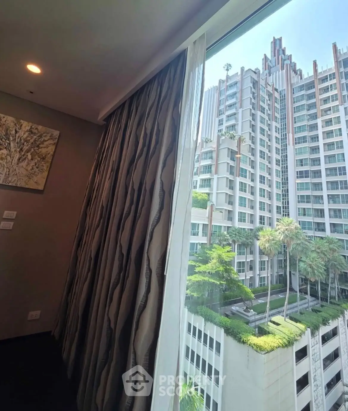 Stunning high-rise view from modern apartment window with lush greenery and urban skyline.