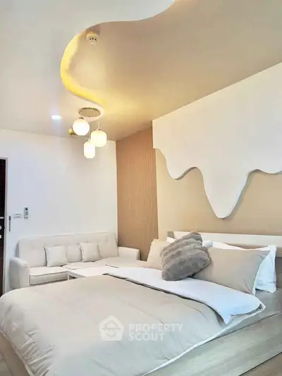 Luxurious modern bedroom with stylish ceiling design and cozy seating area.