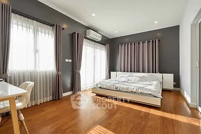 Spacious modern bedroom with wooden flooring and ample natural light