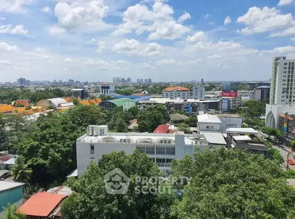 Stunning cityscape view with lush greenery and modern buildings under a bright blue sky.