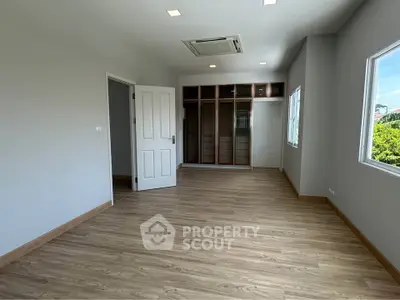 Spacious bedroom with built-in closet and large windows offering natural light.