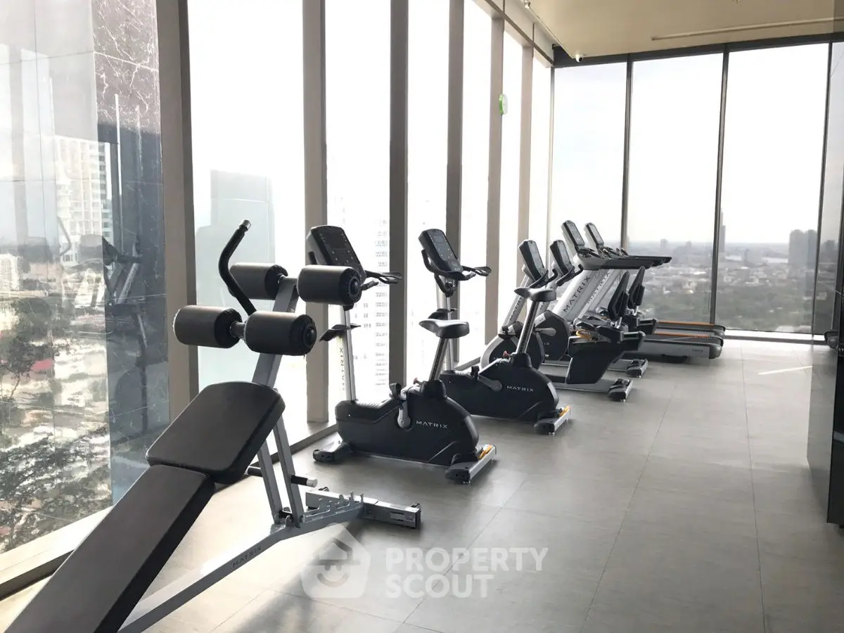 Modern high-rise gym with panoramic city views and state-of-the-art fitness equipment.