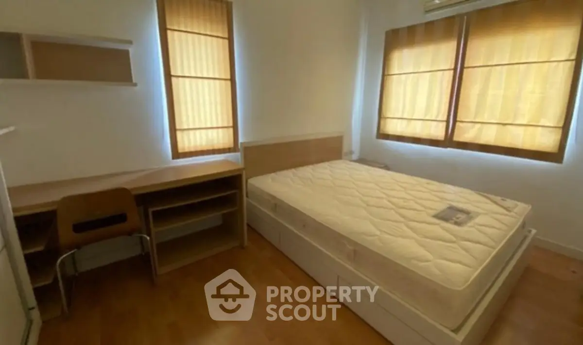 Cozy bedroom with natural light, featuring a comfortable bed and wooden furniture, ideal for restful living.
