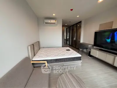 Modern bedroom with sleek furniture and large TV in a stylish apartment.