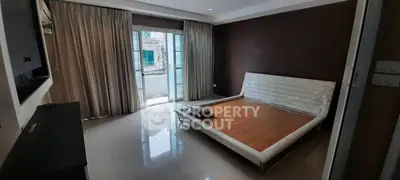 Spacious bedroom with large windows and modern bed frame, offering natural light and city views.