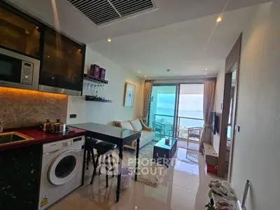 Modern living room with ocean view, featuring open kitchen and cozy seating area.