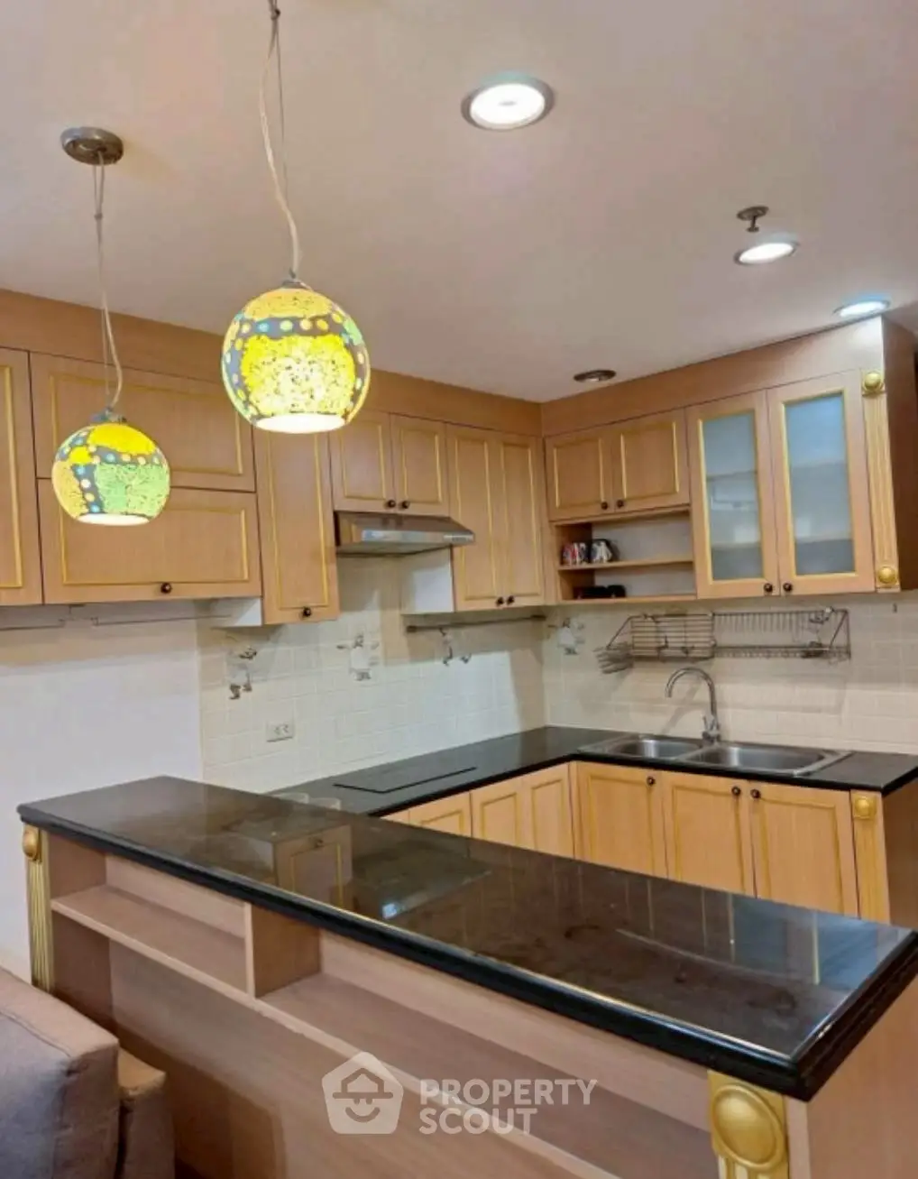 Charming kitchen with wooden cabinets and stylish pendant lights in a cozy home setting.