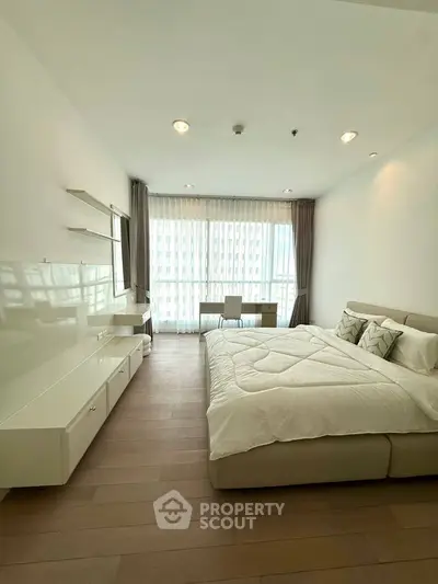 Modern bedroom with large window and stylish decor in a luxury apartment.