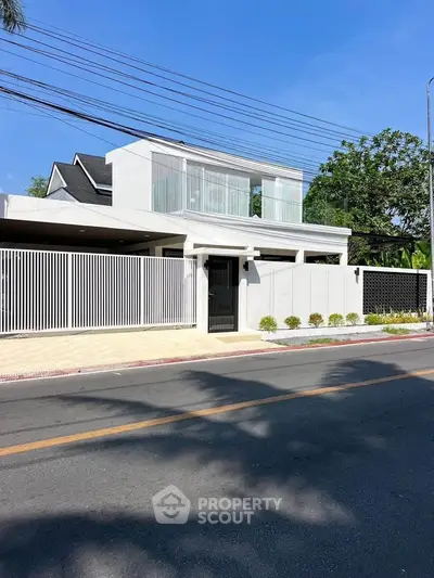 Modern white two-story house with sleek design and spacious balcony in a suburban neighborhood.