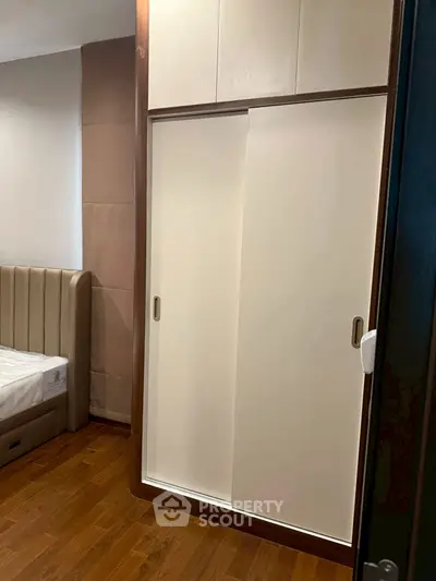 Modern bedroom with sleek sliding wardrobe and wooden flooring