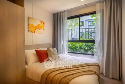 Cozy bedroom with large window and modern decor, offering a serene garden view.