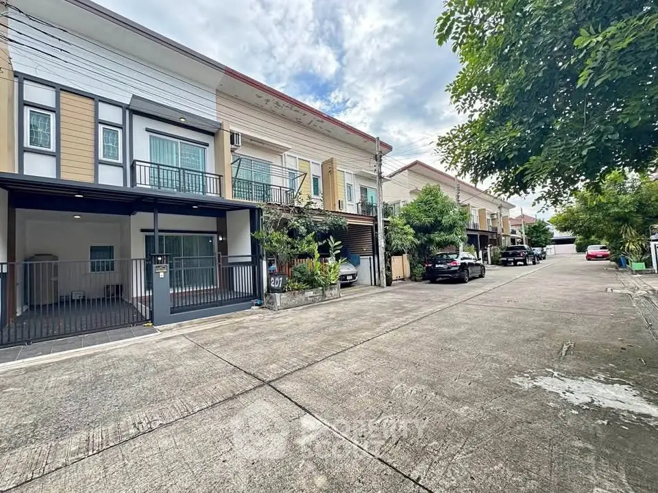 Charming townhouse exterior with driveway and lush greenery in a serene neighborhood.