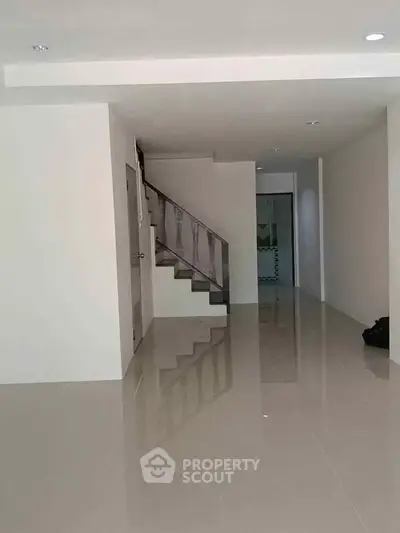 Spacious modern interior with sleek staircase and glossy tiled flooring, perfect for contemporary living.