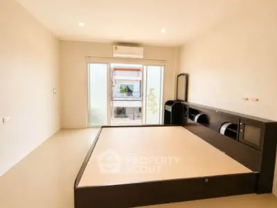 Spacious bedroom with modern bed frame and large window offering natural light.
