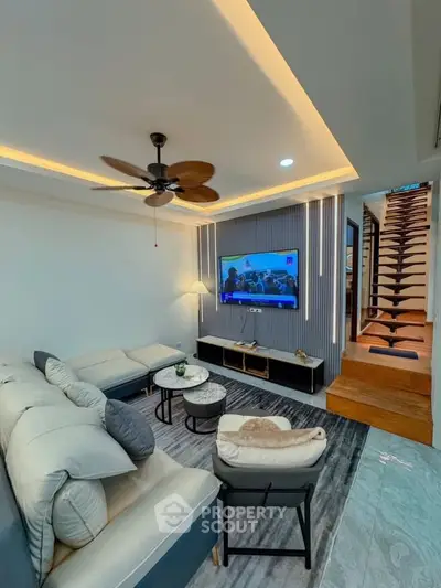 Modern living room with stylish decor and staircase, featuring cozy seating and ambient lighting.
