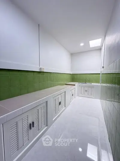 Sleek modern kitchen with green tile backsplash and ample counter space, perfect for culinary enthusiasts.