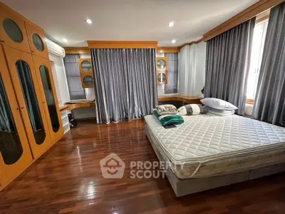 Spacious bedroom with hardwood floors and large windows in modern apartment.