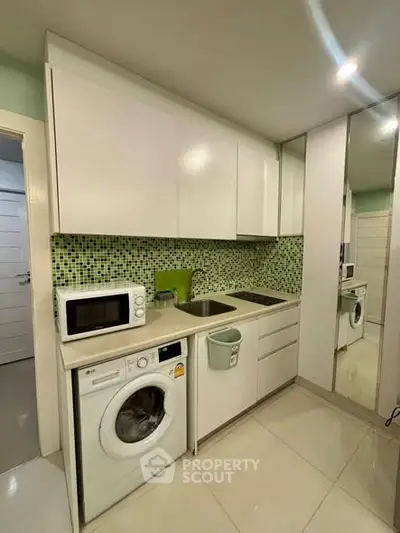Modern kitchen with washing machine and green mosaic backsplash