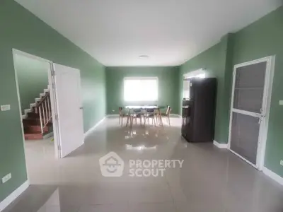 Spacious green-walled dining area with modern furniture and natural light