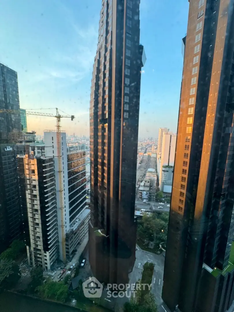Stunning cityscape view with modern skyscrapers and construction crane at sunset.