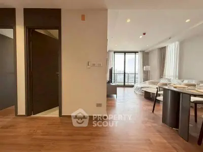 Spacious modern living room with wooden flooring and large windows offering city views.