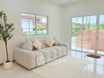 Bright living room with plush sofa and large windows offering garden views