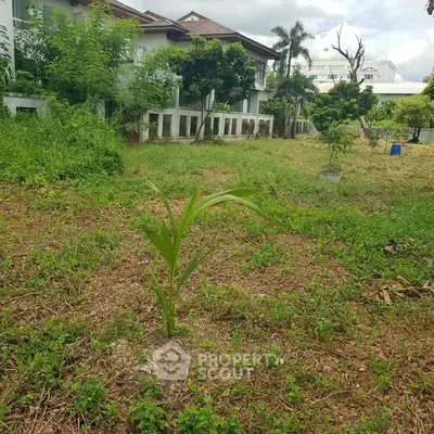 Spacious garden area with lush greenery and residential building in the background.