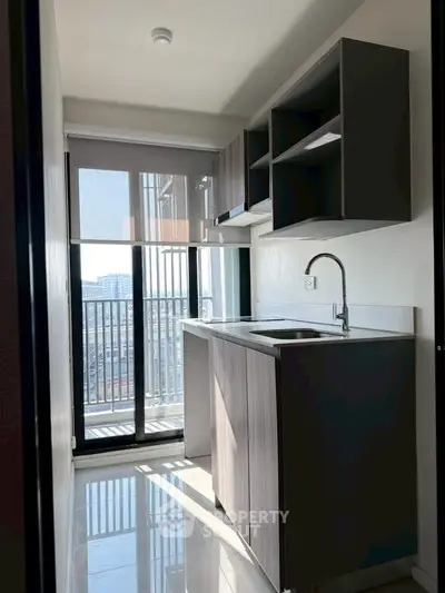 Modern kitchen with sleek cabinetry and balcony view in a high-rise apartment.