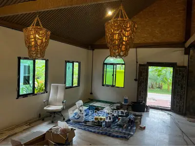 Spacious living room with unique hanging lights and large windows overlooking greenery.
