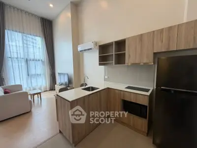 Modern open-layout kitchen with sleek appliances and cozy living area in a stylish apartment.