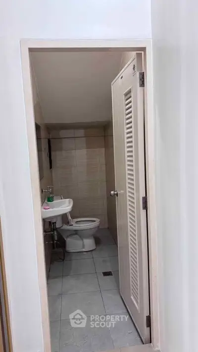 Compact bathroom with modern fixtures and neutral tiles, perfect for efficient space utilization.