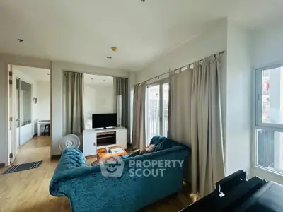 Spacious living room with elegant blue sofa and large windows offering natural light.