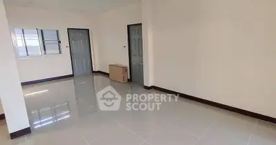 Spacious empty room with tiled flooring and neutral walls, ideal for customization.