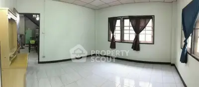 Spacious empty room with tiled floor and large windows, ideal for customization.