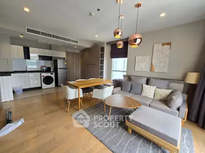 Modern living room with open kitchen, stylish furniture, and washing machine in a cozy apartment.
