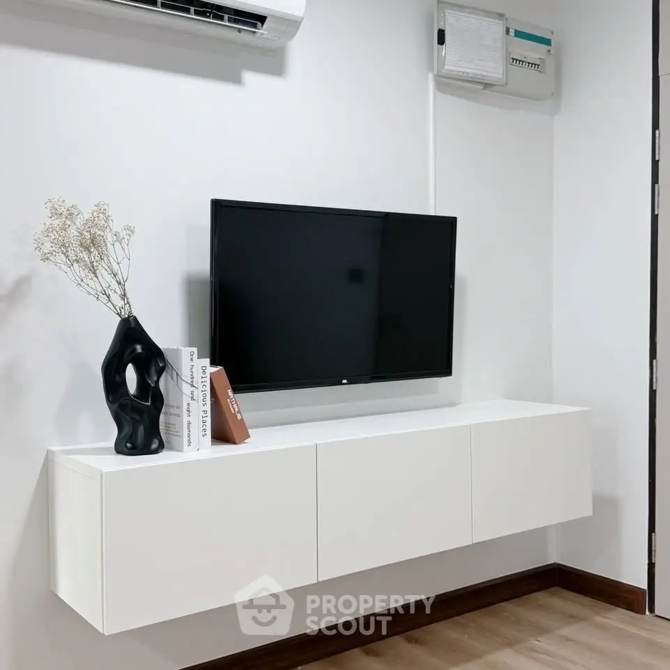 Modern minimalist living room with wall-mounted TV and sleek white cabinet