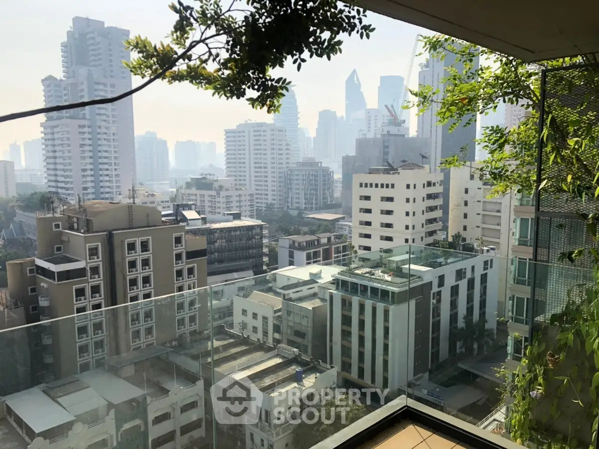 Stunning cityscape view from a modern balcony with lush greenery and skyline backdrop.
